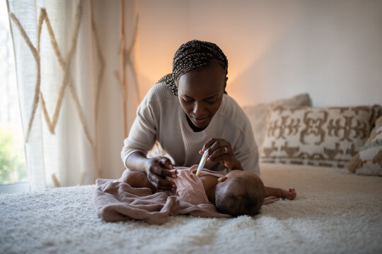 Young mom checking baby temperature in bed 
