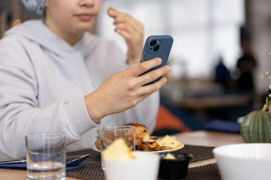 Person in Hijab Using Smartphone While Eating