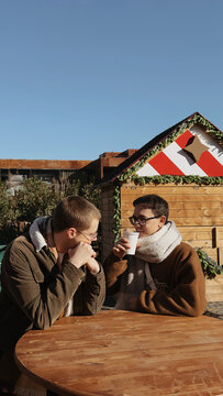 Friends enjoy drinks outside on a sunny winter day together