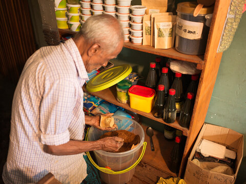 Shop owner measures a scoop of masala curry powder