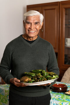 Happy Ederly Man Smiles While Holding a plate with indonesian food