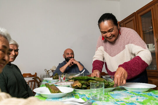 Woman serving a platter of Nasi Bakar to her smiling family at home