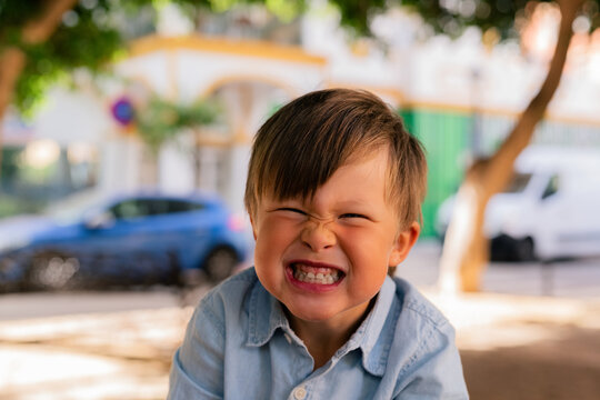 Child Smiles Broadly in Park on Sunny Day in City Street