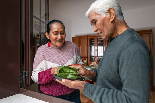 Adult woman smiling at her father while preparing traditional food