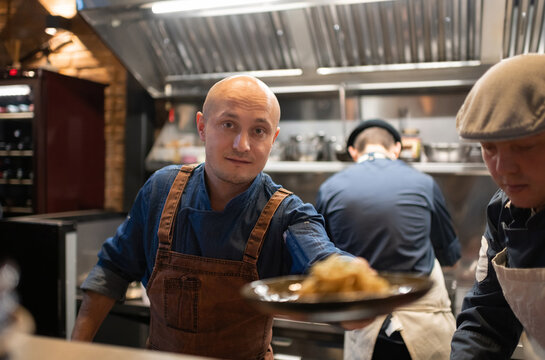Bald chef serving pasta to client