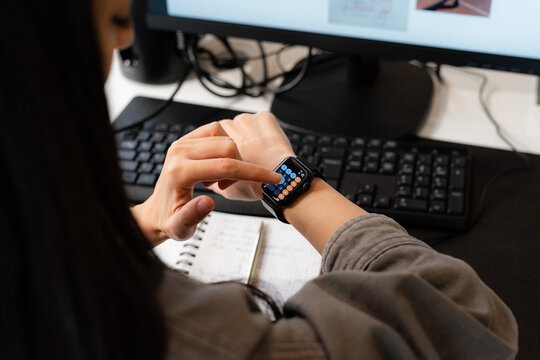 Person Using Smartwatch at a Desk With a Computer and Keyboard