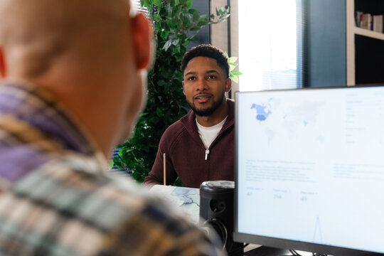 Two Men Discuss Ideas in an Office Setting With a Computer Screen