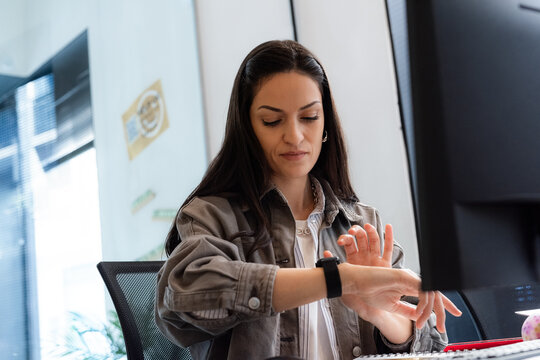 Woman checking smartwatch during work at modern office