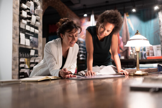 Cheerful woman designer discussing project with black colleague