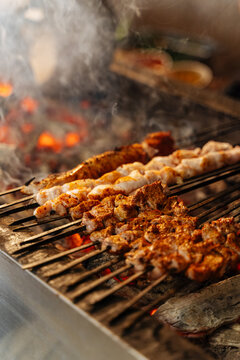Assorted meat skewers grilling over hot coals 
