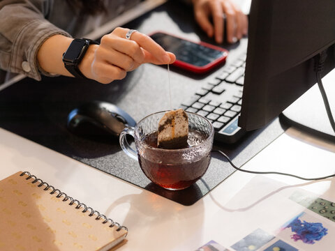 Woman soaking teabag in mug 