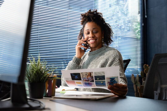Woman Talking on Phone While Reviewing Printed Documents at Desk