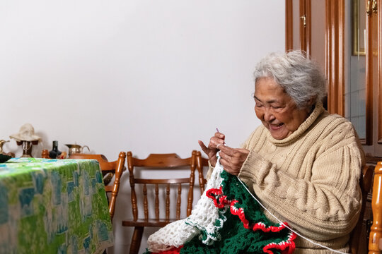 Elderly Woman Crochets in a Cozy Home Setting During Afternoon Hours