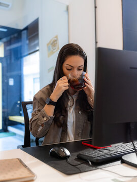 Woman Drinking Tea While Working at a Desk in an Office
