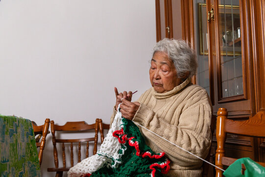 Elderly Woman Knitting Inside a Room With Wooden Furniture