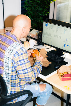Office Worker Enjoys Lunch While Using a Computer in the Workplace