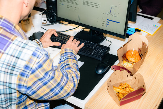 Working at a Desk With Food and Data on the Computer Screen