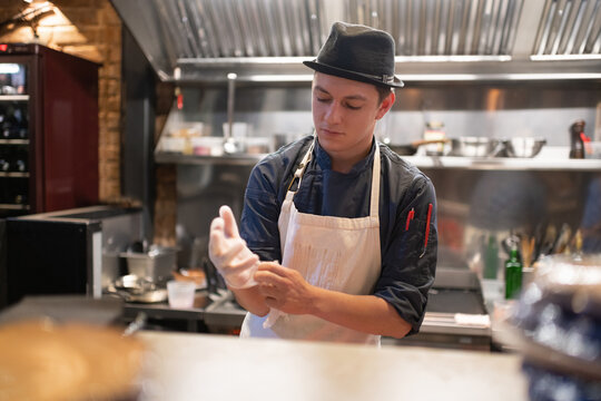 Male cook putting on gloves in kitchen