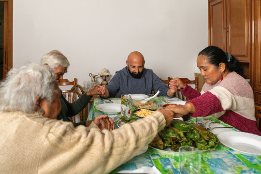 Family praying together before sharing an Indonesian meal