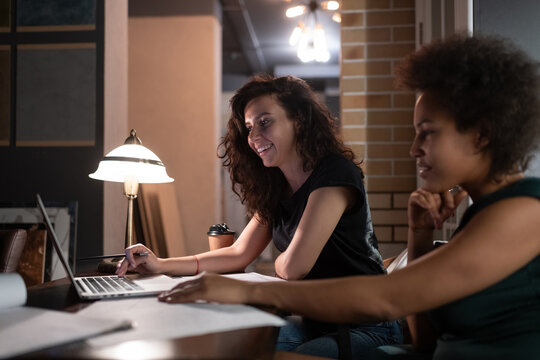 Happy diverse women designers browsing laptop