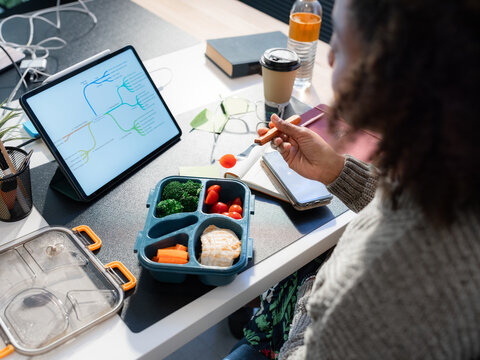 Woman eating from lunchbox at work 