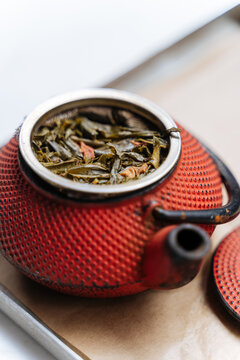 Loose leaf tea brewing in red cast iron teapot 