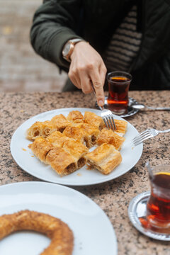 Person eating pastry with Turkish tea