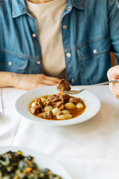 Person eating lamb stew with pearl onions