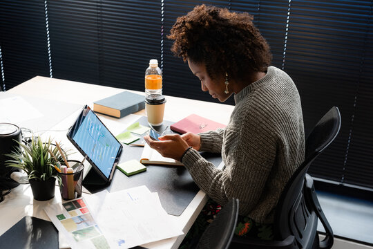 Woman using app on smartphone while working at office 