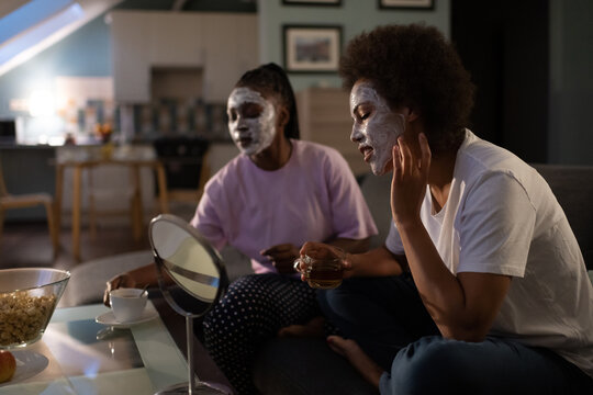 Multiracial woman smearing mask during sleepover