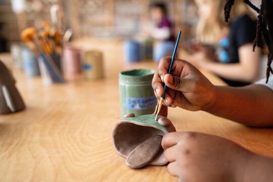 Student Painting Handmade Clay Sculpture in Art Class