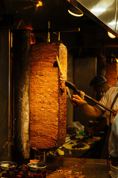 Chef slicing doner kebab meat on vertical rotisserie