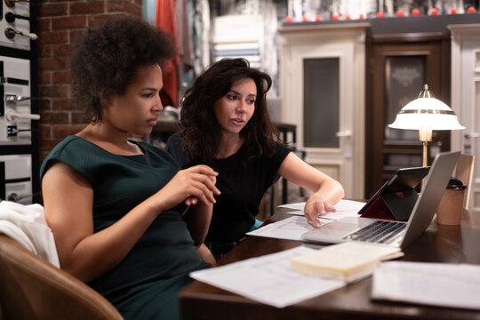 Female designers analyzing drafts on laptop