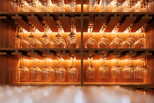 Rows of beautiful wine glasses hanging in wooden cupboard with light