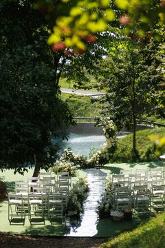 Beautiful white chairs between glass path in green yard on pond shore