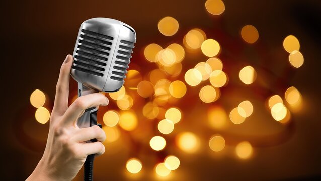 Hand holding a retro microphone on background
