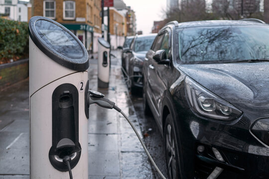 Electric Vehicle Charging Station is in Use on a Rainy Day in the City