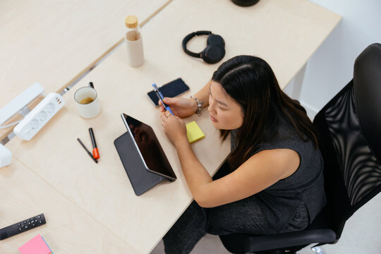Asian woman working focused at office desk with tablet