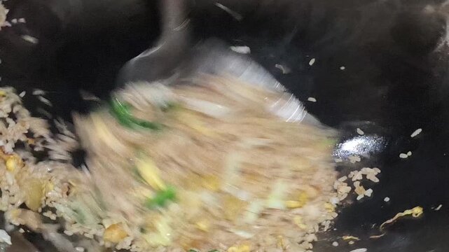 Delicious fried rice being cooked in a hot wok with fresh ingredients, creating rich aromas, vibrant colors, and an appetizing traditional culinary experience