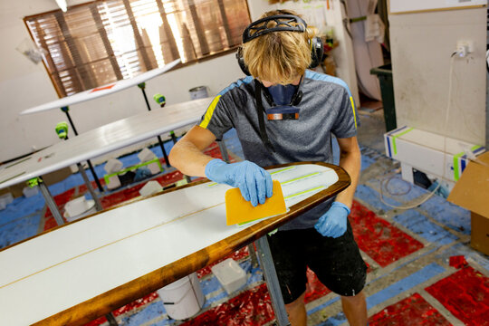 Shaper glassing surfboard deck in Australia
