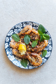 Grilled shrimp with lemon and mint on patterned plate