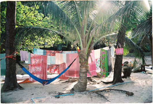 Colorful cloths hang on a line between palm trees at a beach