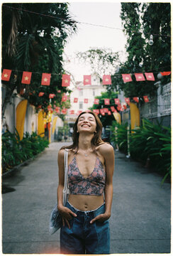 Woman smiles in alley decorated with flags during daytime in Vietnam