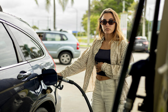 Woman pumps fuel into a car at a gas station during in Australia