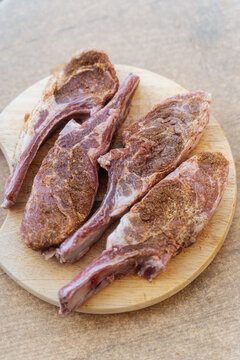 Raw lamb chops with seasoning on wooden board