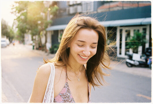 Woman smiles while walking down a street in a city