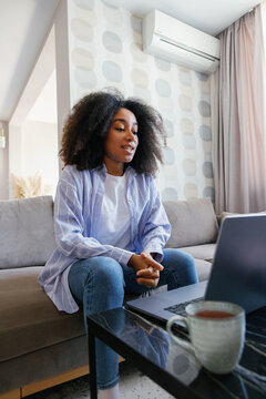 Black woman having video call on laptop on sofa at living room at home