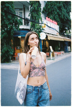 Woman drinks from cup while enjoying time on the street of Saigon