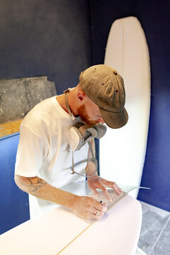 Surfboard shaper marking fin placement in Australia