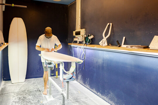 Surfboard shaper at work in shaping room 